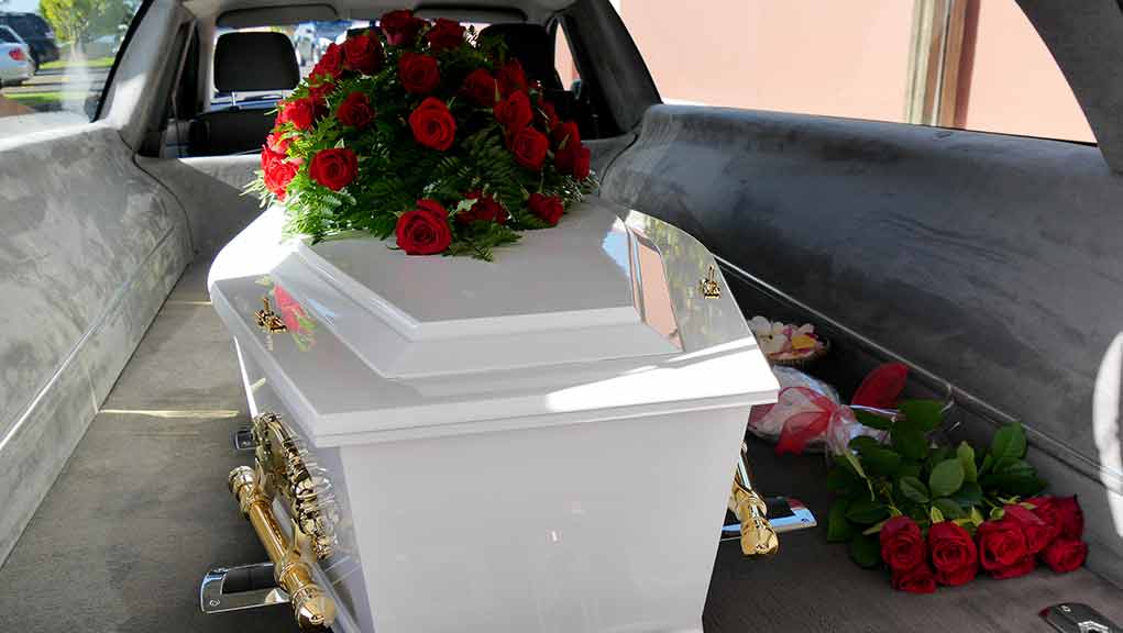 687733453 featured image White coffin with red roses inside a hearse