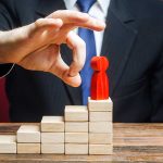 Hand placing red figure on wooden block stairs