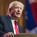 Trump Unveils New National Treasure Hiding in Plain Sight Man in suit speaking at podium with flag background