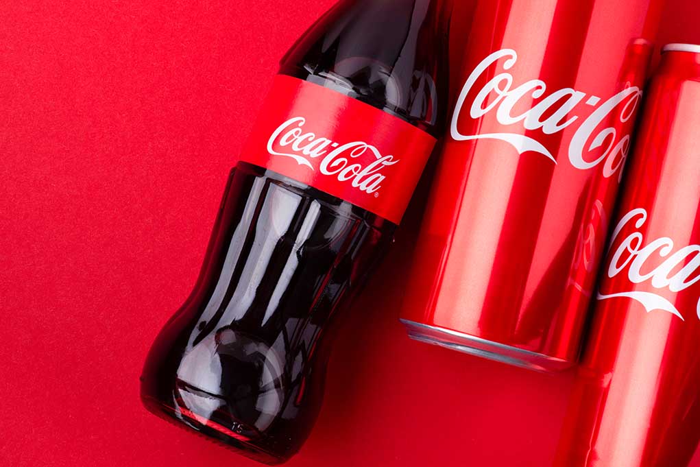 Coca-Cola bottles and cans on red background