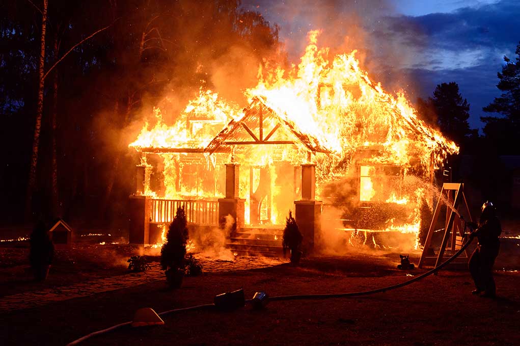 House engulfed in flames with firefighters present