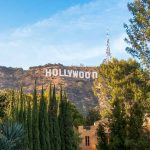Hollywood sign on hill surrounded by trees and buildings.