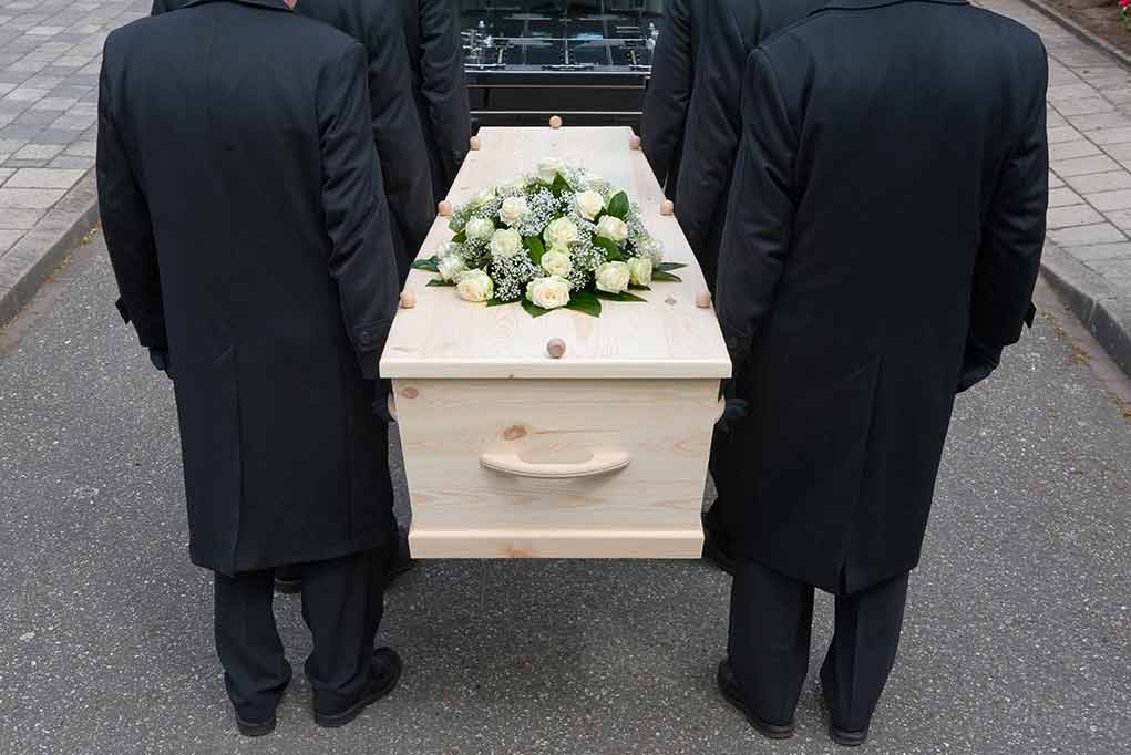 144558722 featured image Four people carrying a coffin with white flowers