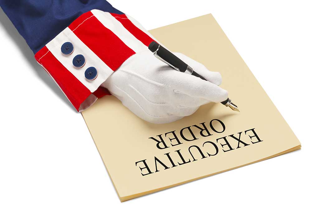 Gloved hand writing executive order labeled paper