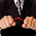 Person breaking red pencil with both hands