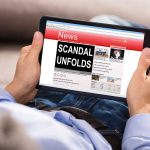 Scandal Erupts – A Media’s Lie Just Got Officially Exposed Person reading tablet with headline scandal unfolds