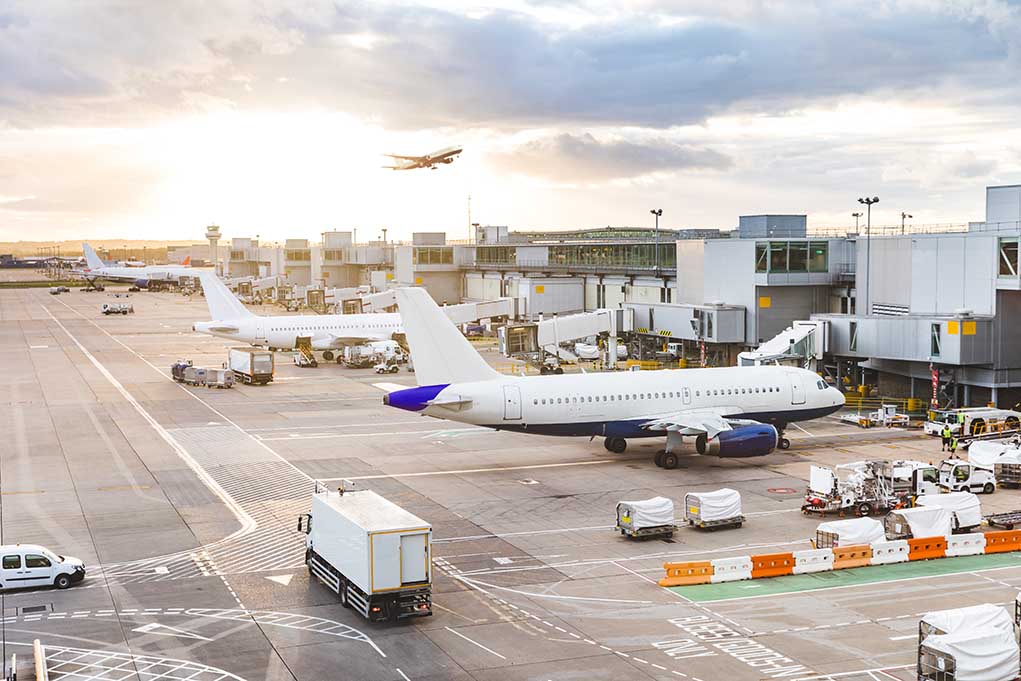 Airport with airplanes runway and terminal at sunset