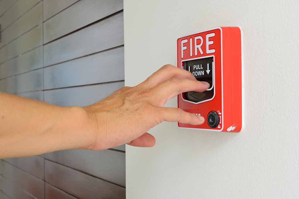 Hand reaching to pull fire alarm lever