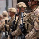 Soldiers in camouflage standing in a line with rifles
