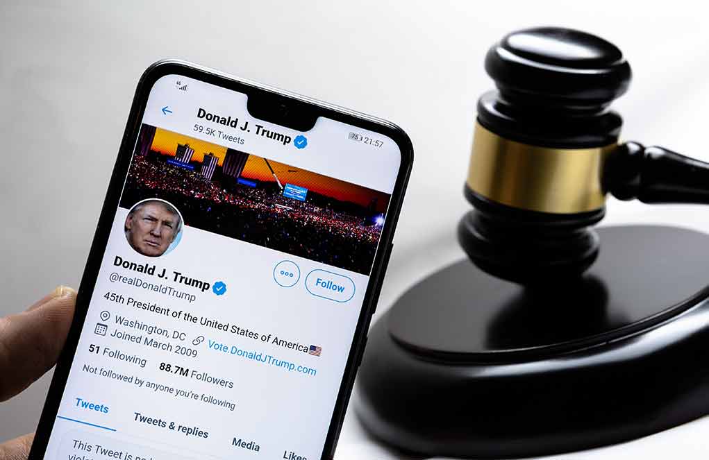 Smartphone displaying Twitter profile beside a judge gavel