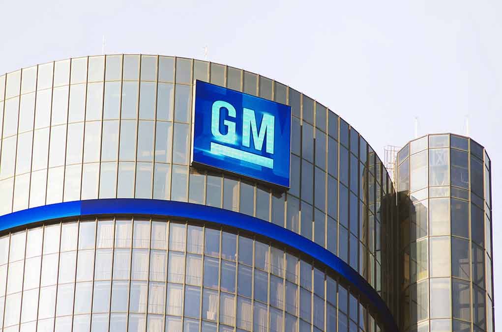 Glass building with large GM logo on top.