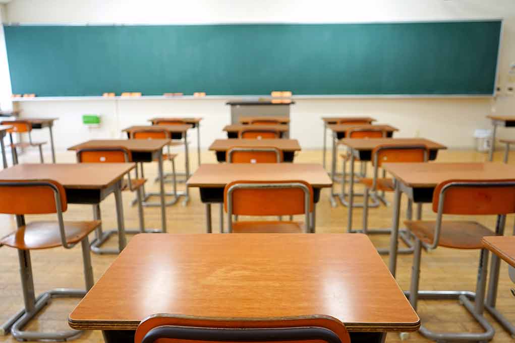 Classroom with wooden desks and empty green chalkboard