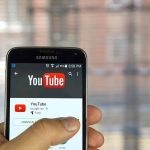 Hand holding smartphone with YouTube app open