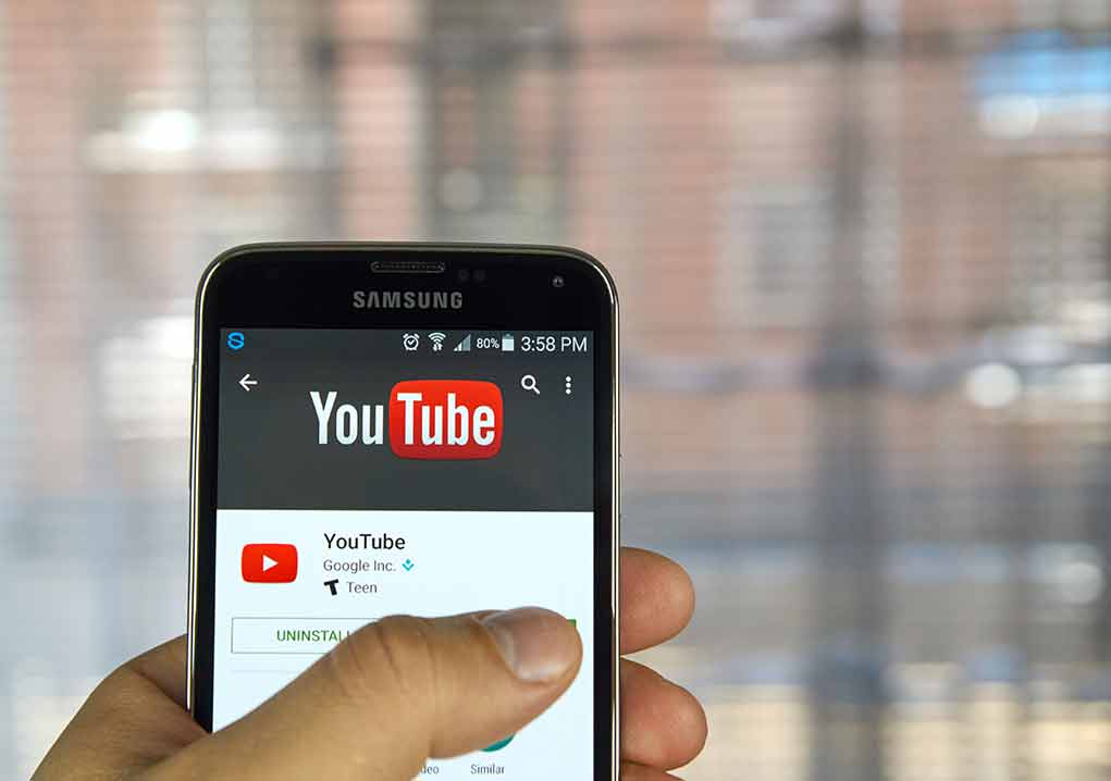Hand holding smartphone with YouTube app open