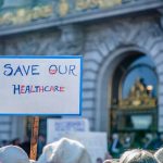 WHO Power Grab Sparks Global Backlash Sign reading Save Our Healthcare at protest