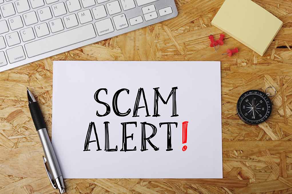 594304802 featured image Scam alert message on a wooden desk.