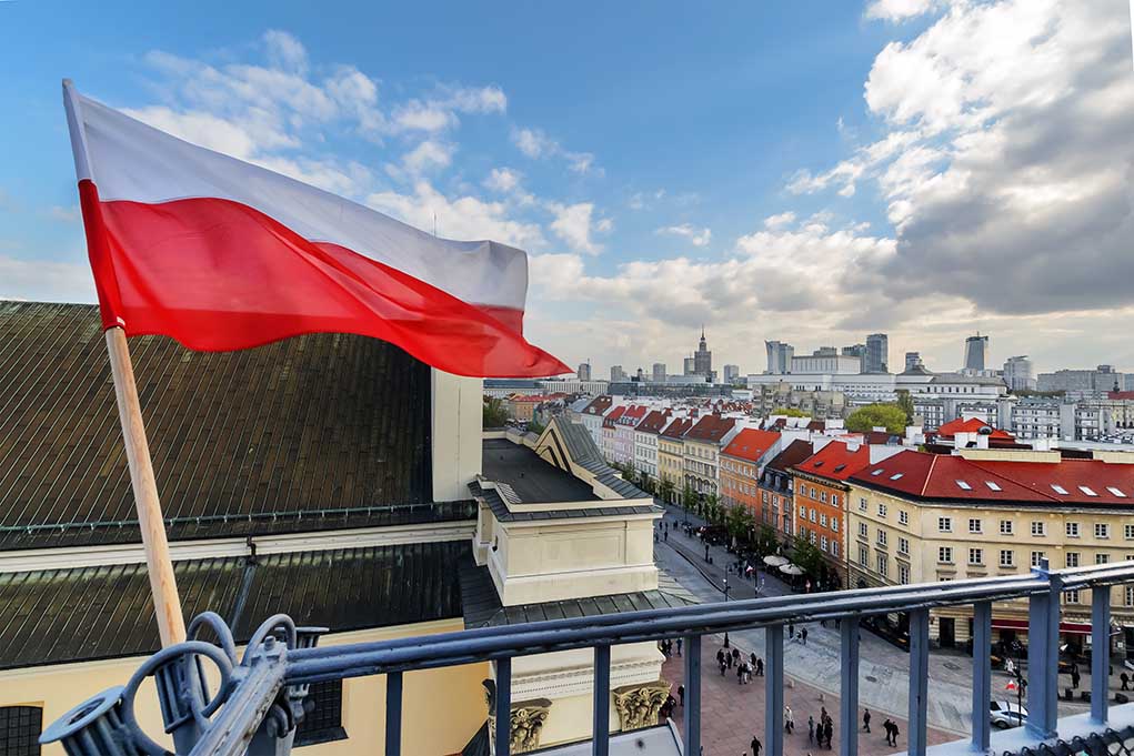 Polish flag over cityscape with buildings and cloudy sky