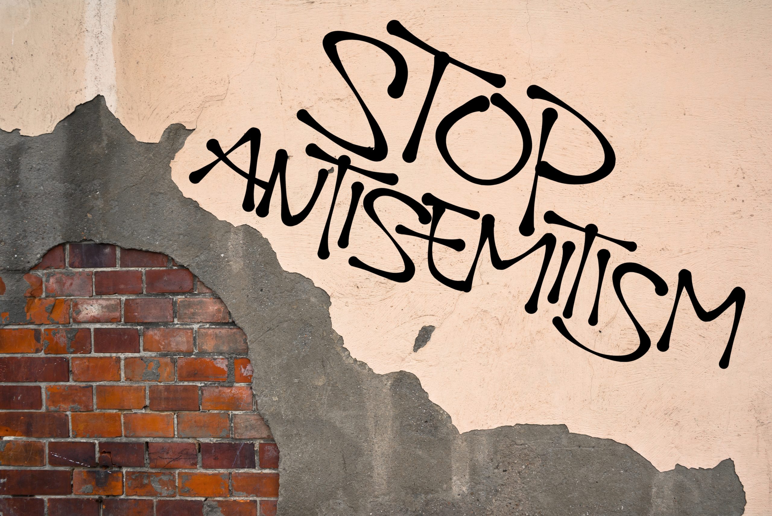 Stop antisemitism graffiti on a worn brick wall