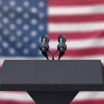 Podium with microphones American flag background