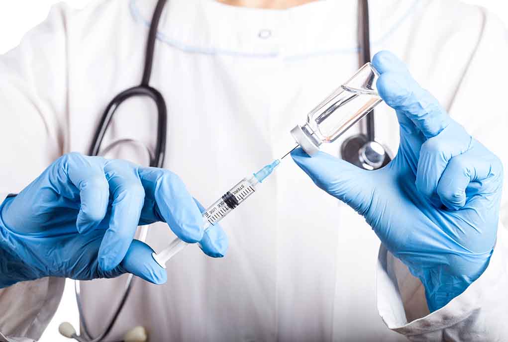 Doctor filling syringe with vaccine from vial