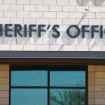 Deported Criminal HUNTS U.S. Prosecutor with Knife Sheriffs Office sign on brick building faade