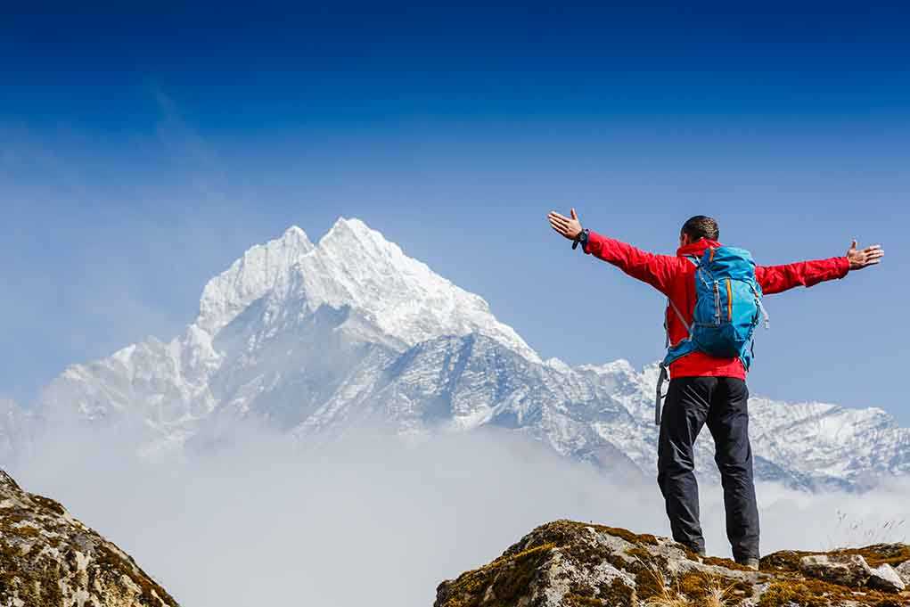 Hiker with arms outstretched in front of snowy mountains