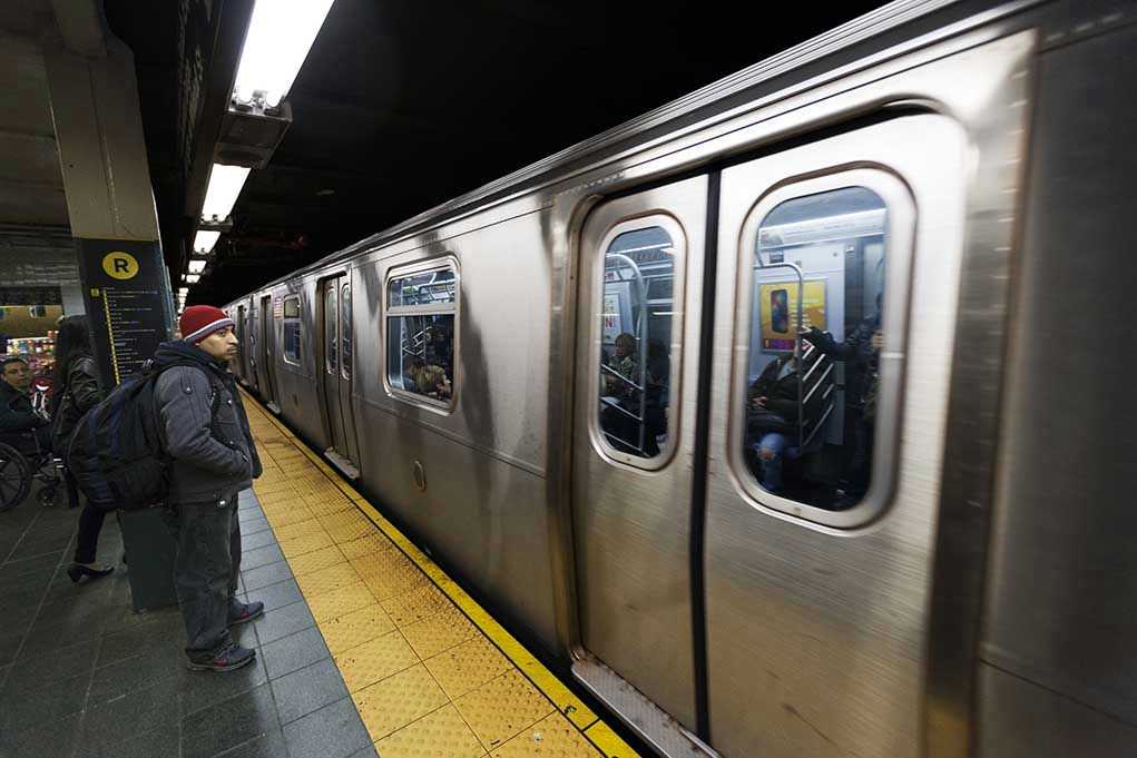 Man waiting at subway platform with departing train