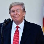 Man in suit and tie speaking at podium