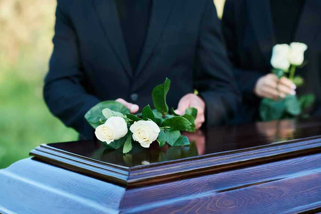 2360876213 People placing white roses on a casket