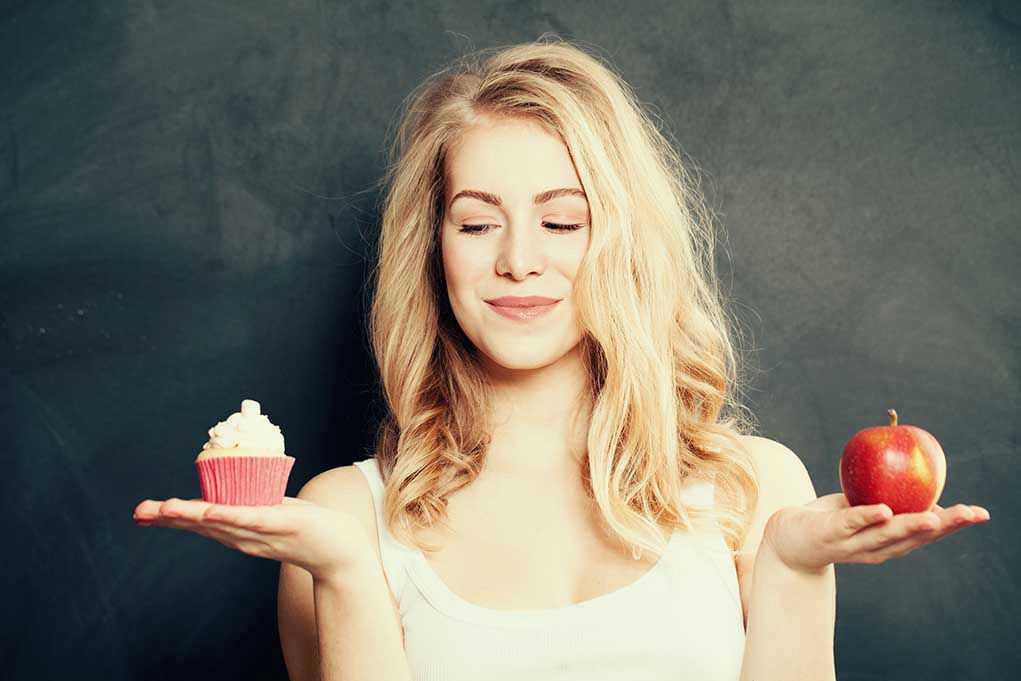 Woman holding a cupcake and an apple