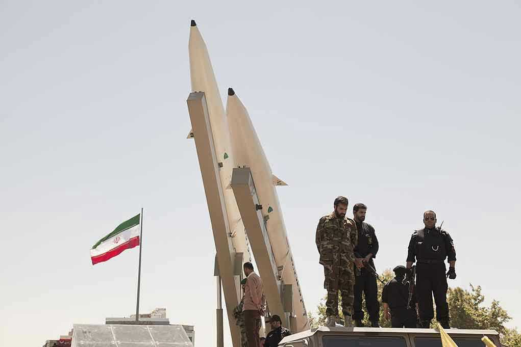 681421708 Military personnel beside missiles and Iranian flag