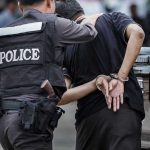 Massive Black Market Marijuana Operation Exposed Police officer arrests handcuffed person