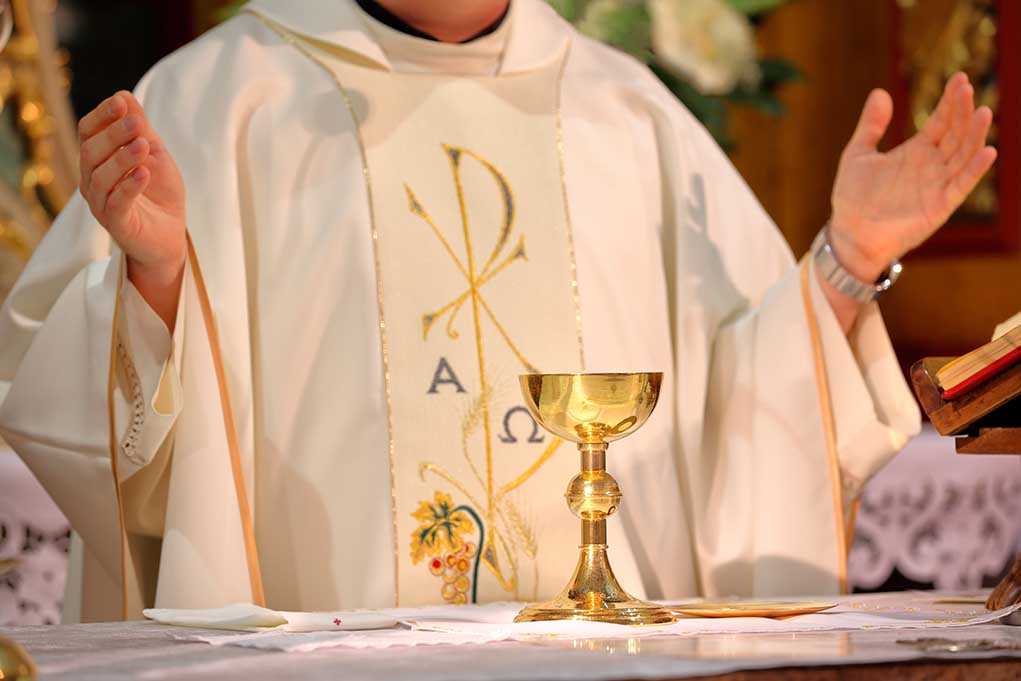 A priest performing a religious ceremony with a golden chalice