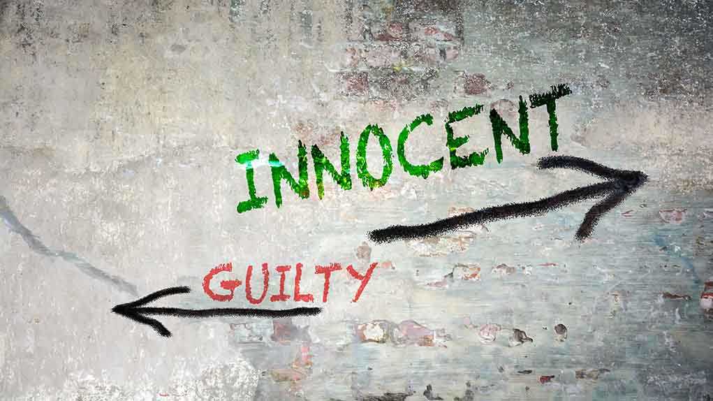 Graffiti on a wall depicting the words 'INNOCENT' and 'GUILTY' with arrows