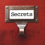 Champion’s Secret Addictions Rock Sports World Metal label holder saying Secrets on wood background