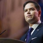 Explosive Call: End Hamas Now, Says Rubio Man in suit speaking at podium.