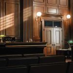Prosecutors CAUGHT—Witness Declared Dead Turns Up Alive Empty courtroom with judges bench and wooden decor.