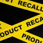 Yellow tape with product recall text on black background.
