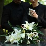 Aide’s Fiery Death Shocks Congress Mourners in black holding white flowers at funeral.