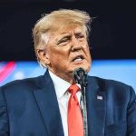 Trump Slams UN: Escalator Sabotage Speculated Man in suit speaking at a microphone.