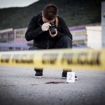 SHOCKING Shooting: Innocent Dad Falls Crime scene photographer behind police tape with evidence marker.