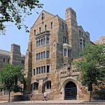 Trump UNLEASHES Federal Crackdown on Elite Universities Historic university building with stone facade and surrounding trees