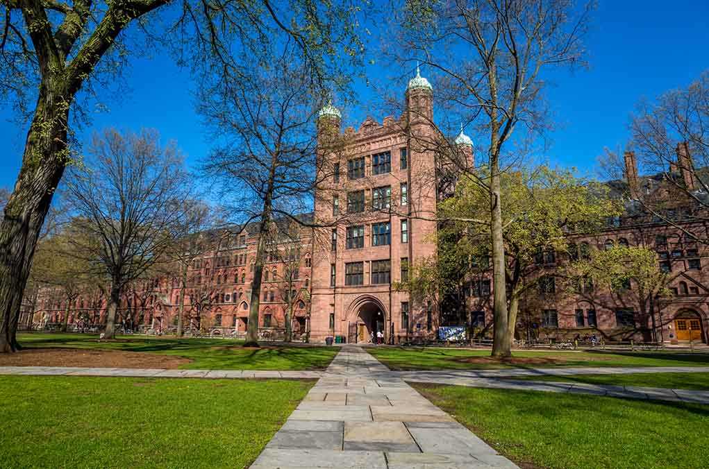 shutterstock_192516893.jpg Historic university building surrounded by green grass and trees under a blue sky