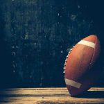 Coach ATTACKS 7-Year-Old During Game An American football resting on a wooden surface against a dark background