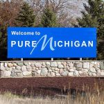 GHOST SHIP Found After 139 Years Welcome sign for Pure Michigan with a blue background and stone base