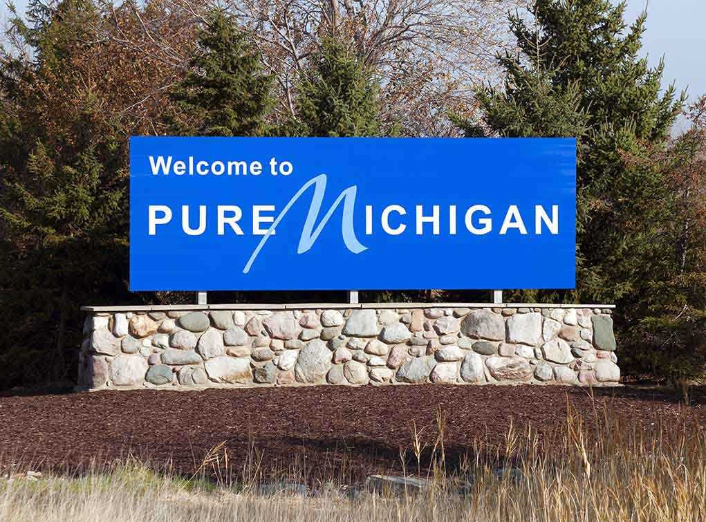 shutterstock_64887757.jpg Welcome sign for Pure Michigan with a blue background and stone base