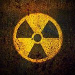 Nuclear Smuggling SHOCK – Chinese Trio Arrested Yellow radiation warning symbol on rusty metal surface.
