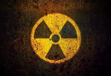 Nuclear Smuggling SHOCK – Chinese Trio Arrested Yellow radiation warning symbol on rusty metal surface.