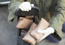 LATEST U.S. Military STRIKE — Drug Cartel Boat Obliterated Person handling packages wearing gloves and green jacket.