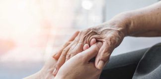 Young hands holding an elderly persons hand.